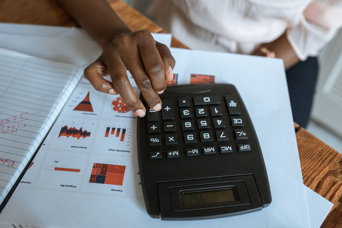 Hands using a calculator over financial charts